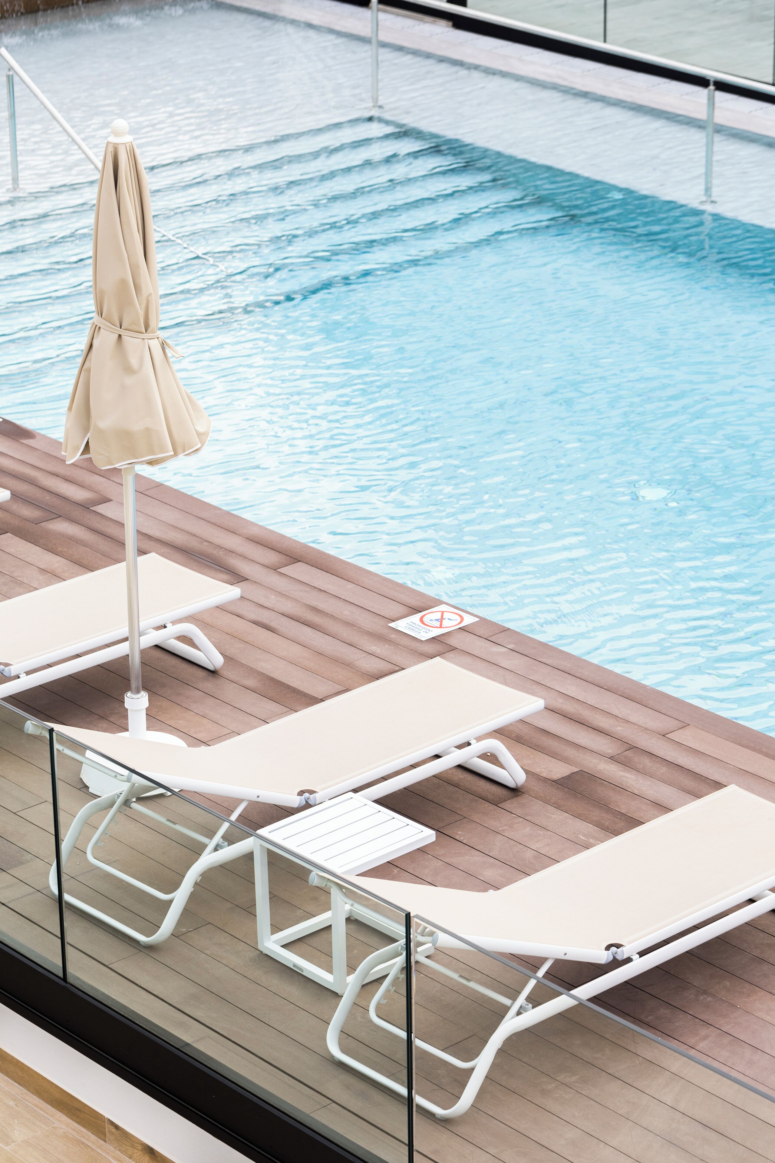 A poolside area with lounge chairs and an umbrella.