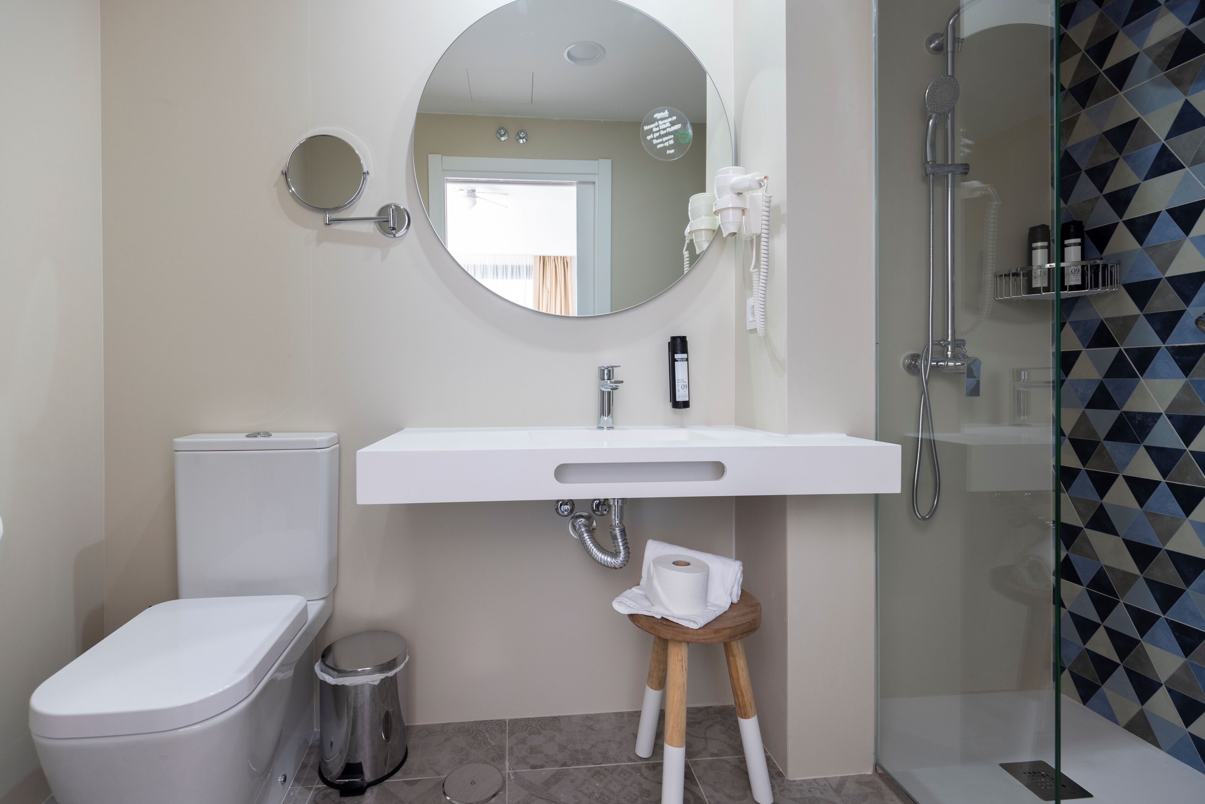 Une salle de bain équipée de toilettes, d’un lavabo, d’un miroir et d’une douche.