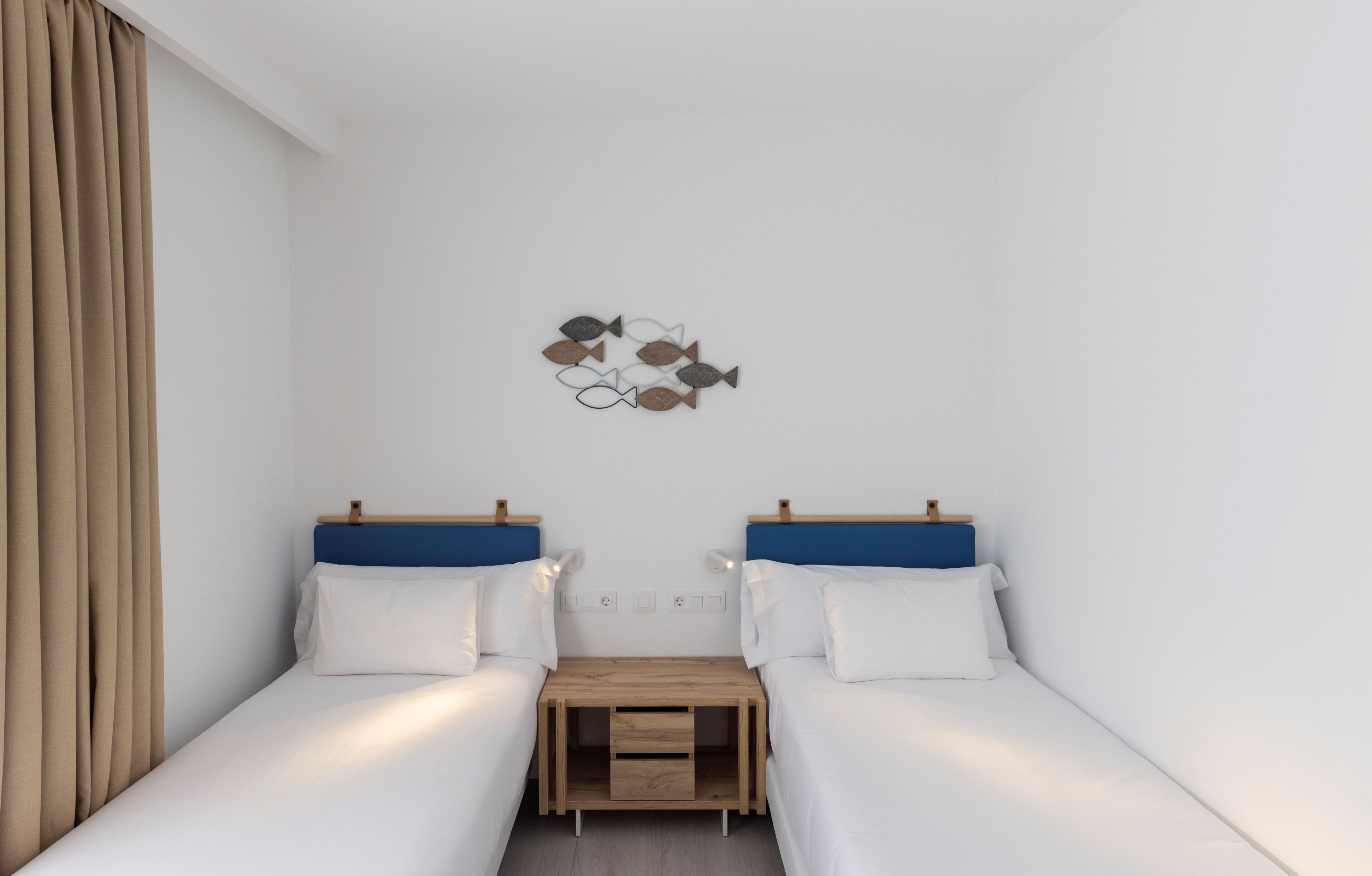 Ein Schlafzimmer mit zwei Einzelbetten, einem Nachttisch aus Holz und einer Wanddekoration.