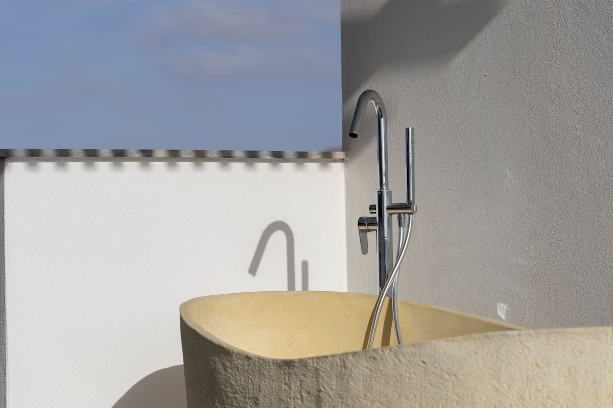 A bathroom with a bathtub, a shower, and a wall-mounted faucet.
