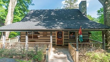 Step into this charming cabin, featuring a cozy porch and a stone chimney, surrounded by the tranquility of the forest.