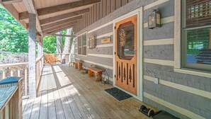 A wooden deck with a covered area, a wooden door with a window, and a bench.