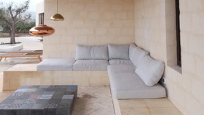A modern interior with a concrete ceiling, a light-colored sofa, and a patterned coffee table.