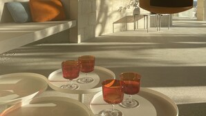 A modern interior with a seating area, a hanging light fixture, and a table with glasses.