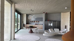 A modern living room with a dining area, white sofas, and a kitchen in the background.