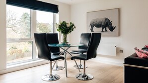 A modern dining area with a glass table, black chairs, and a large window with a view of trees. - Luxury 2 Bed/2 Shower Room Apartment in Bath City (Bath)