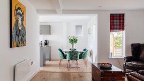 Un salon moderne comprenant un coin repas, un canapé en cuir marron et une malle ancienne.