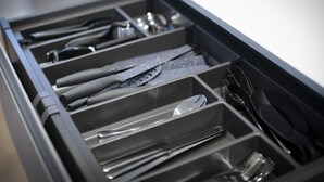 A drawer with compartments containing various kitchen utensils and cookware.