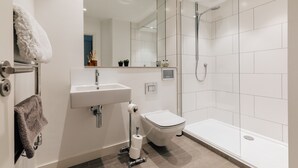 A modern bathroom with a sink, toilet, and shower.