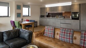 A modern living room with a leather sofa and a dining table with chairs.