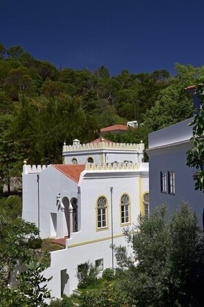 A white building with yellow trim and arched windows, surrounded by greenery. - Pure Monchique Hotel (Monchique)