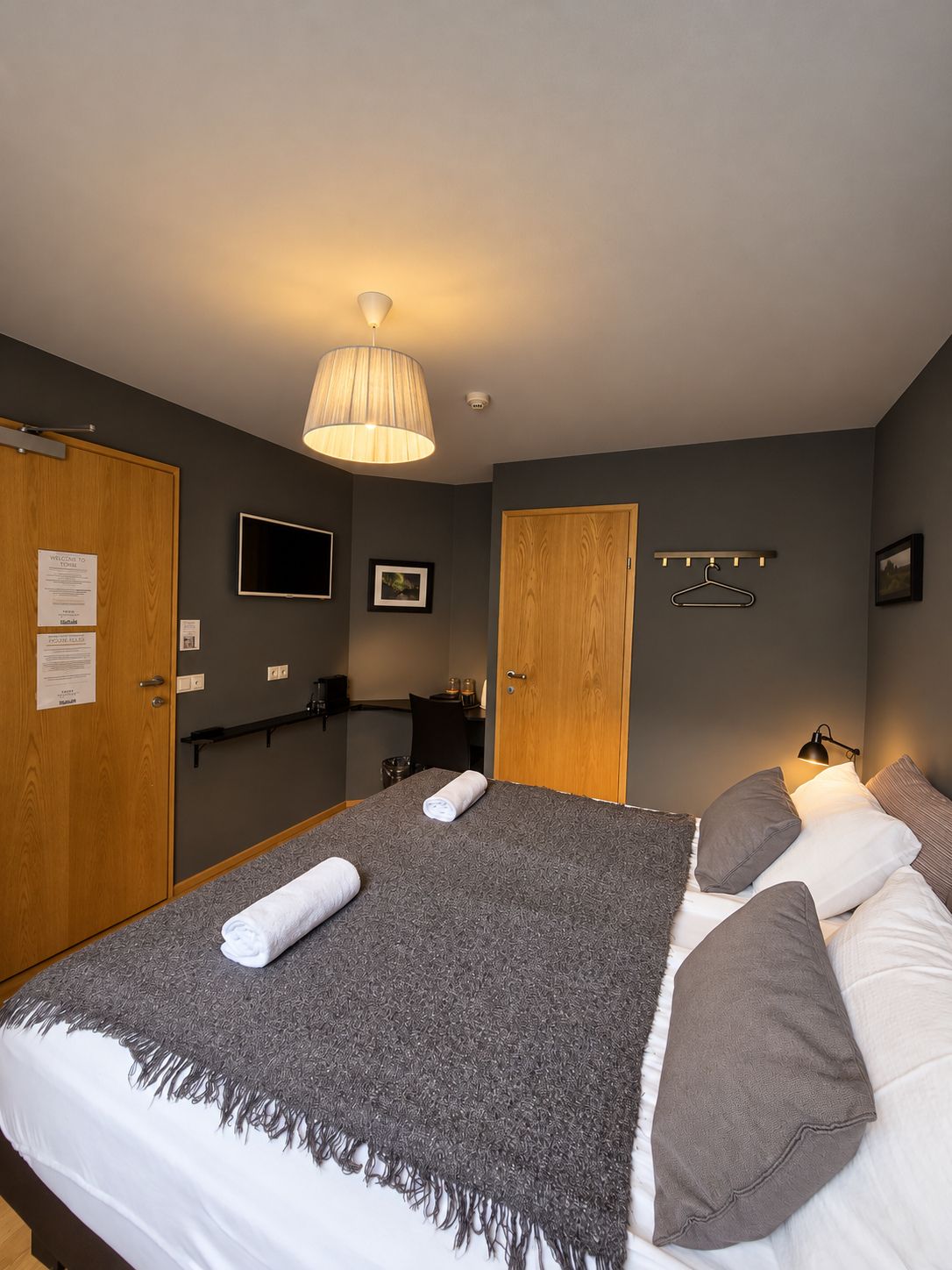 A hotel room with a bed, a television, a desk, and a wardrobe.