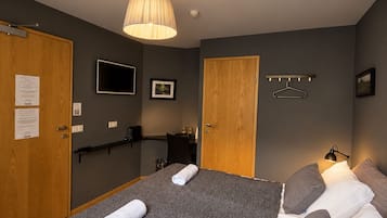 A hotel room with a bed, a television, a desk, and a wardrobe.