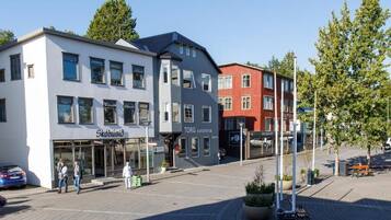 En moderne bygning med butiksvindue, der viser skiltene "Skohusied" og "Torg Guesthouse".
