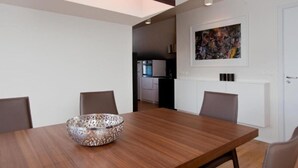 Une salle à manger moderne avec une table en bois, un vase décoratif et un tableau au mur.