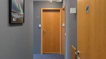 A hallway with a wooden door, a framed picture of the aurora borealis, and a carpeted floor.