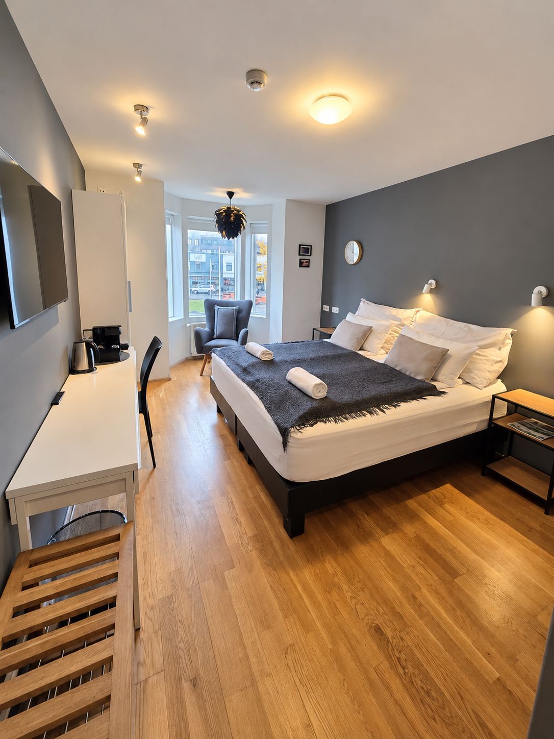 Ein modernes Schlafzimmer mit einem Bett, Nachttischen, einem Schreibtisch und einem Sessel.