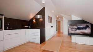 Une cuisine moderne avec des meubles blancs, un plan de travail foncé et un plancher en bois.