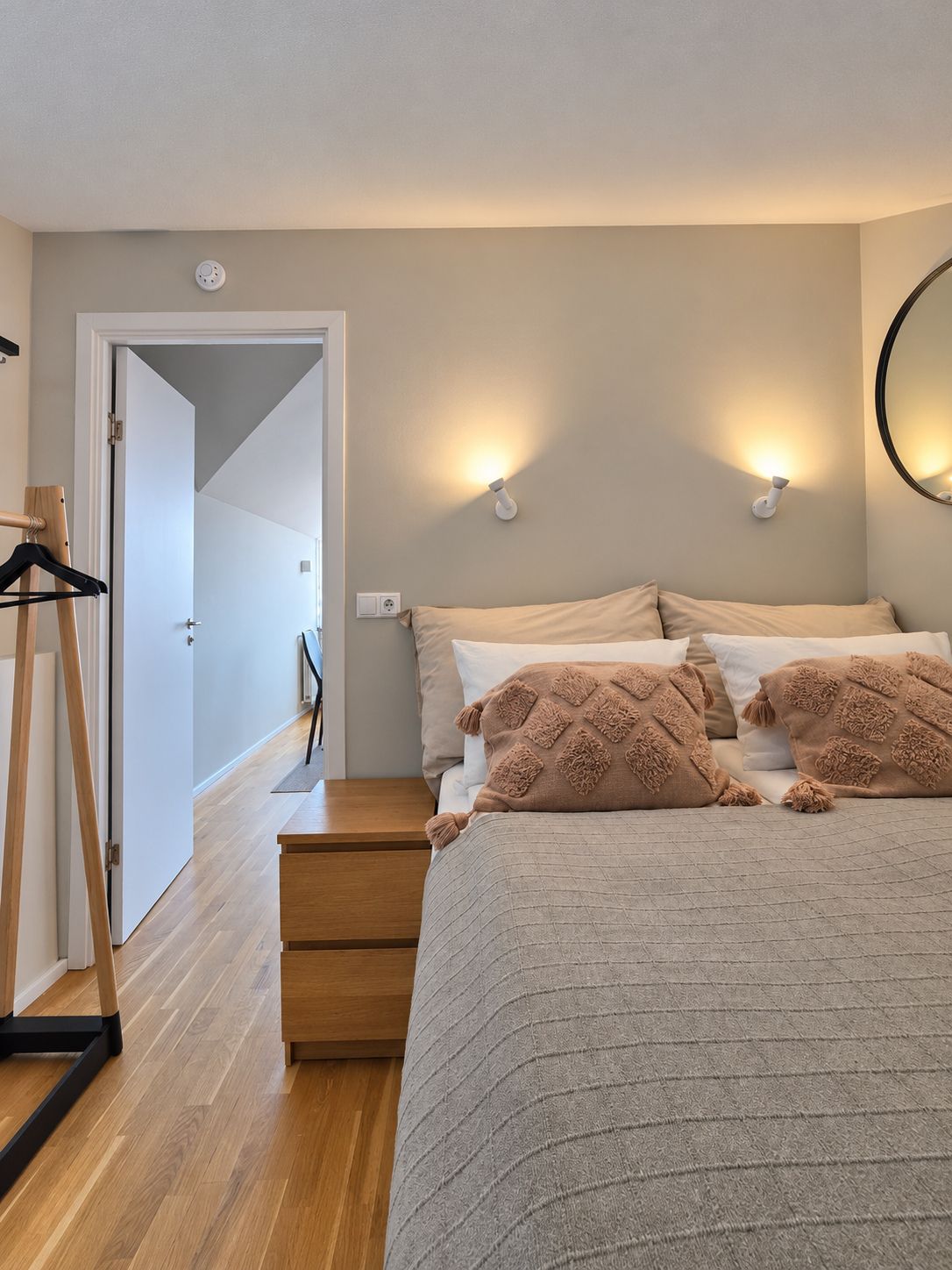 Un dormitorio con cama, mesitas de noche, armario y puerta que da a otra habitación.