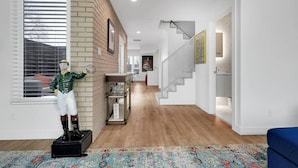 Un intérieur moderne avec un escalier, une statue représentant un sportif et un tapis à motifs.