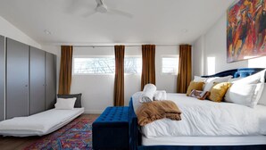 Une chambre d’hôtel moderne avec un grand lit, un petit canapé, un bureau et une armoire.