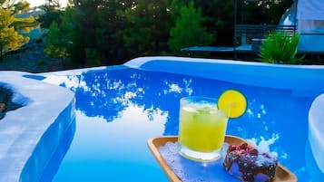 A poolside setting with a drink and dessert on a tray.