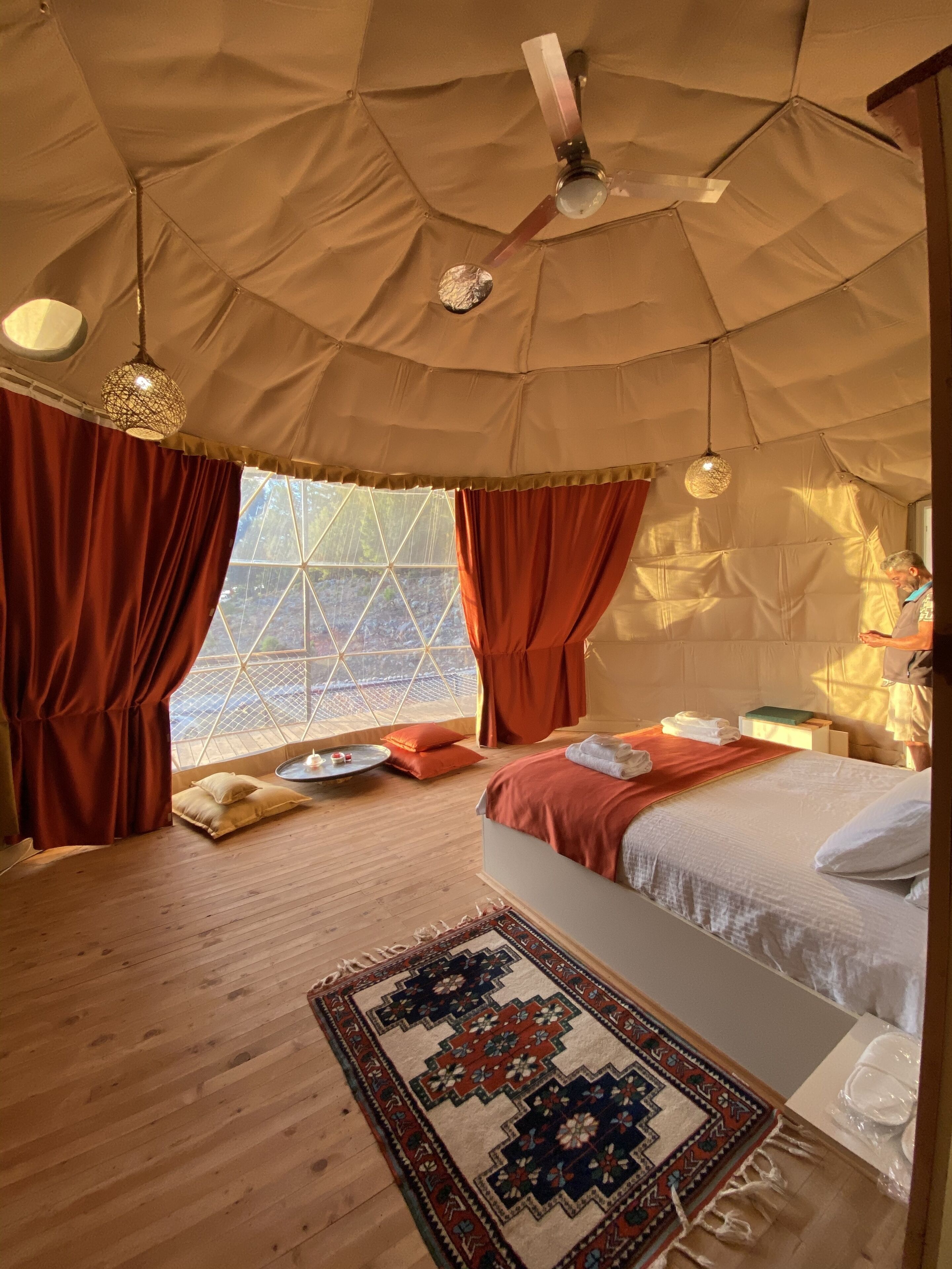 A tented room with a bed, a round table, and a patterned rug.