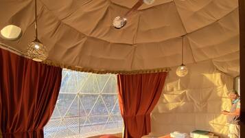 A tented room with a bed, a round table, and a patterned rug.