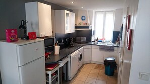 Une cuisine de taille réduite équipée d’un lave-linge, d’un évier et d’un réfrigérateur.