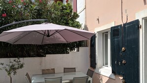 A patio with a table and chairs, an umbrella, and a potted plant. - Apartment Biarritz - Quartier Saint Martin (Biarritz)