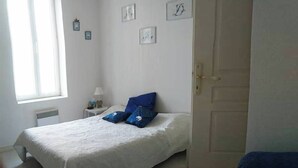 A bedroom with a bed, a nightstand, a window, and a door. - Apartment Biarritz - Quartier Saint Martin (Biarritz)