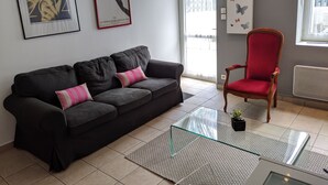A living room with a black sofa, a red chair, a glass coffee table, and two framed posters on the wall. - Apartment Biarritz - Quartier Saint Martin (Biarritz)