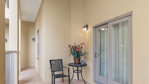 A narrow corridor with a chair and a table, a potted plant, and a sliding glass door.