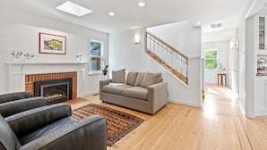 A modern living room with a fireplace, a sofa, a coffee table, and a staircase. - Casita Palo Alto - 2 Bed 2 Bath / Private Back Yard / WiFi (Palo Alto)