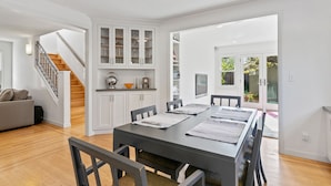 A modern kitchen with white cabinets, a dining area with a long table and chairs, and a staircase leading to another level. - Casita Palo Alto - 2 Bed 2 Bath / Private Back Yard / WiFi (Palo Alto)