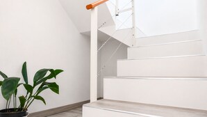 Un escalier avec une main courante en bois et des balustrades en métal, menant à l’étage supérieur.