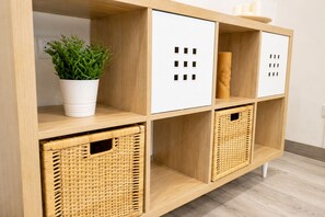 Een houten opbergkast met verschillende vakken, waaronder rieten manden en een potplant.