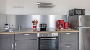 Une cuisine moderne équipée d’appareils électroménagers en acier inoxydable, d’un four à micro-ondes, d’une machine à café et d’une casserole posée sur le plan de travail.