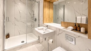 A modern bathroom with a glass-enclosed shower, a white sink, and a wooden vanity. - Luxurious ONE Bedroom Apartment IN Bond Street (Chelmsford)