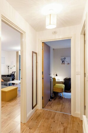 Enter a spacious living area with a sofa, coffee table, and chair, featuring a small table with a lamp.