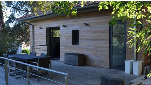 A wooden deck with outdoor furniture, a glass door entrance, and a small window.