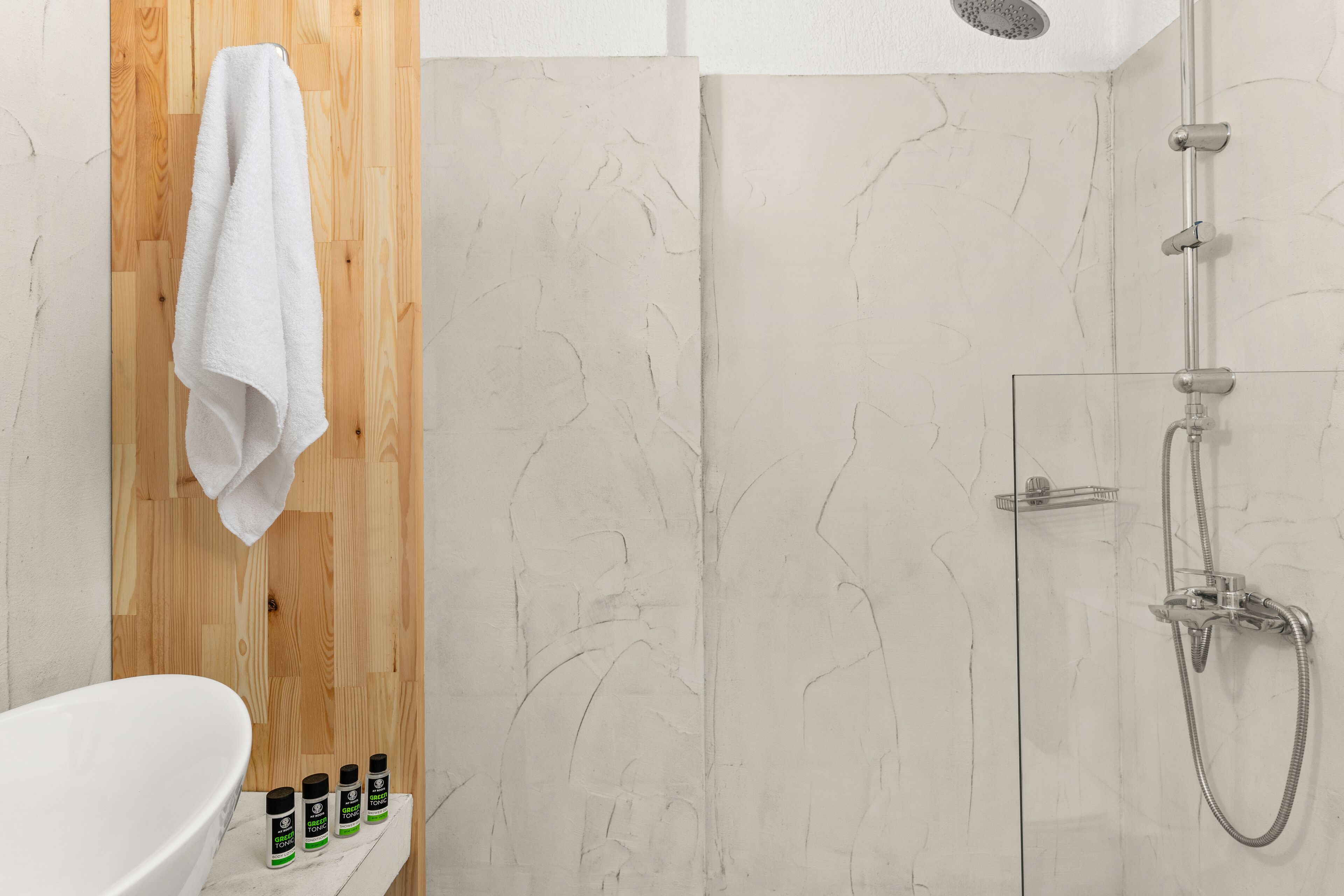 Un baño con pared de paneles de madera, un lavabo blanco y una cabina de ducha de vidrio.