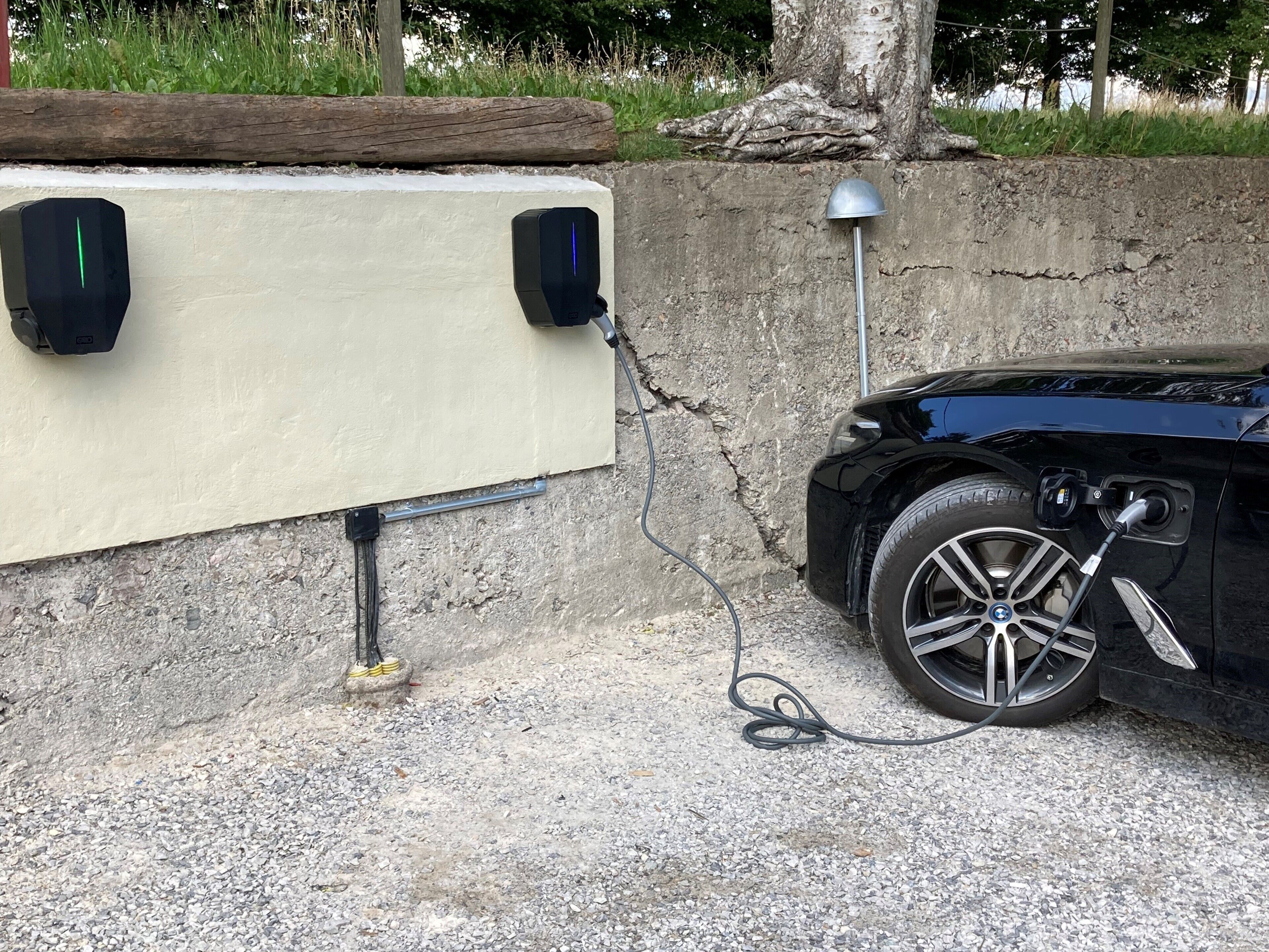 Ein schwarzes Auto, geparkt neben einer Betonmauer mit einer Ladestation.