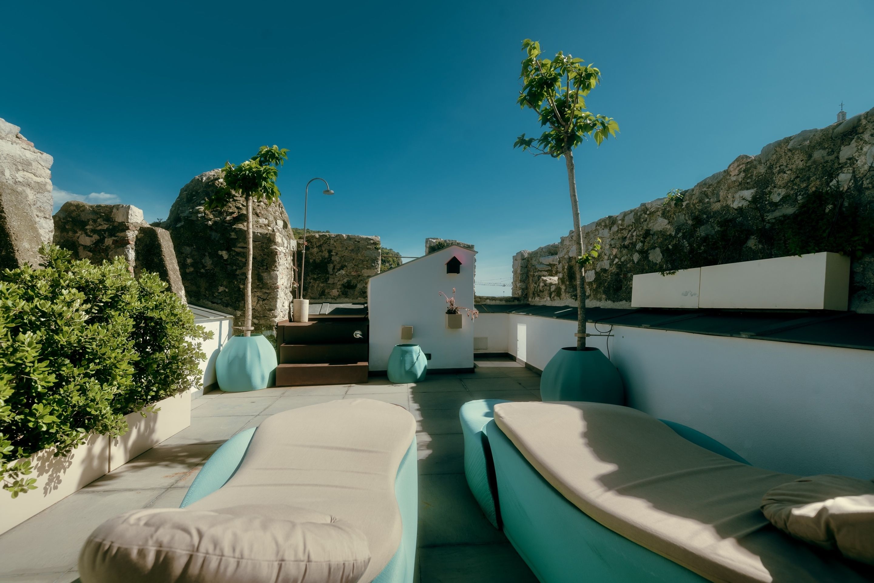 Una terraza en la azotea con zonas de estar, una pequeña construcción y vistas del paisaje circundante.