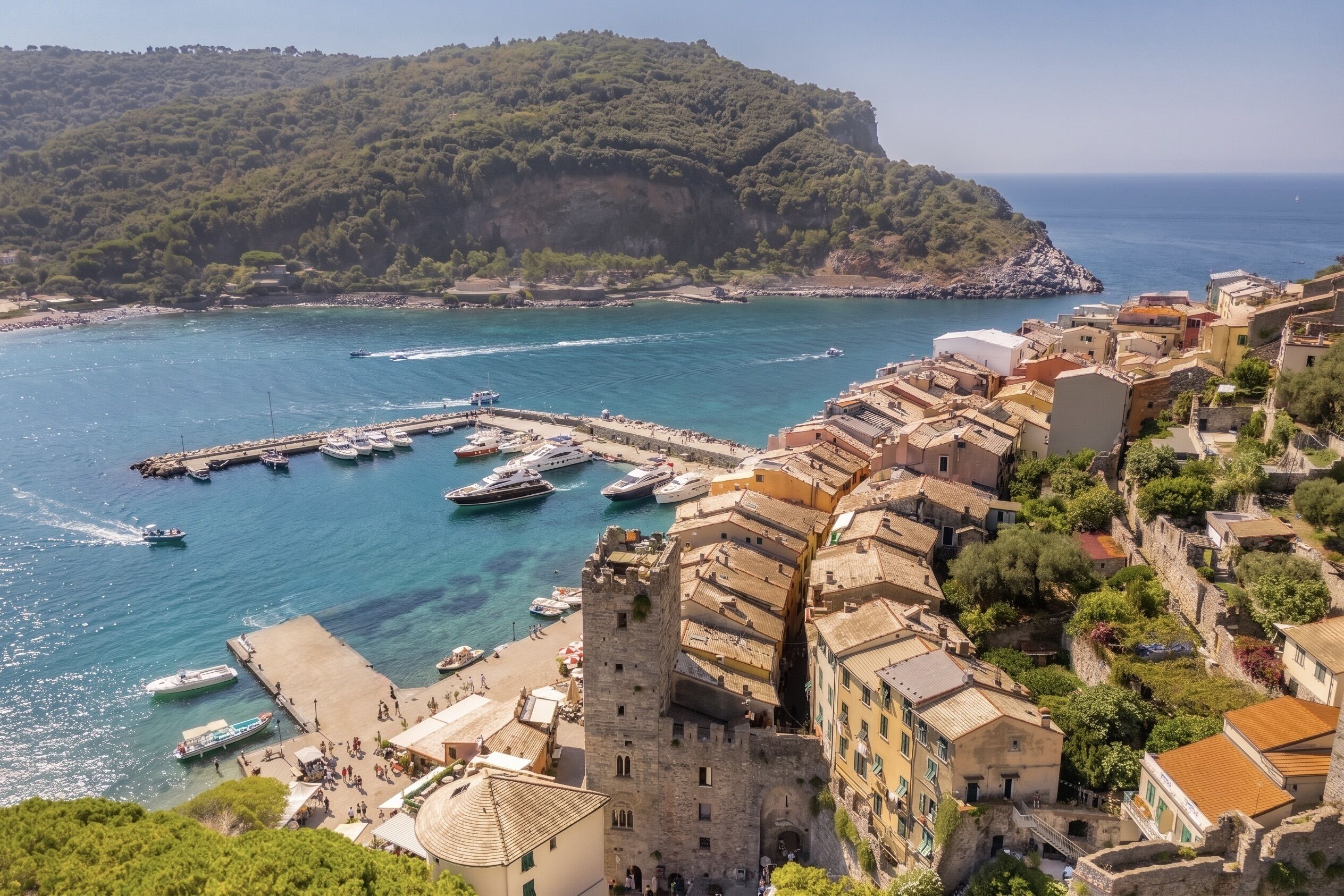 A coastal town with historic buildings, a marina with boats, and a prominent tower.