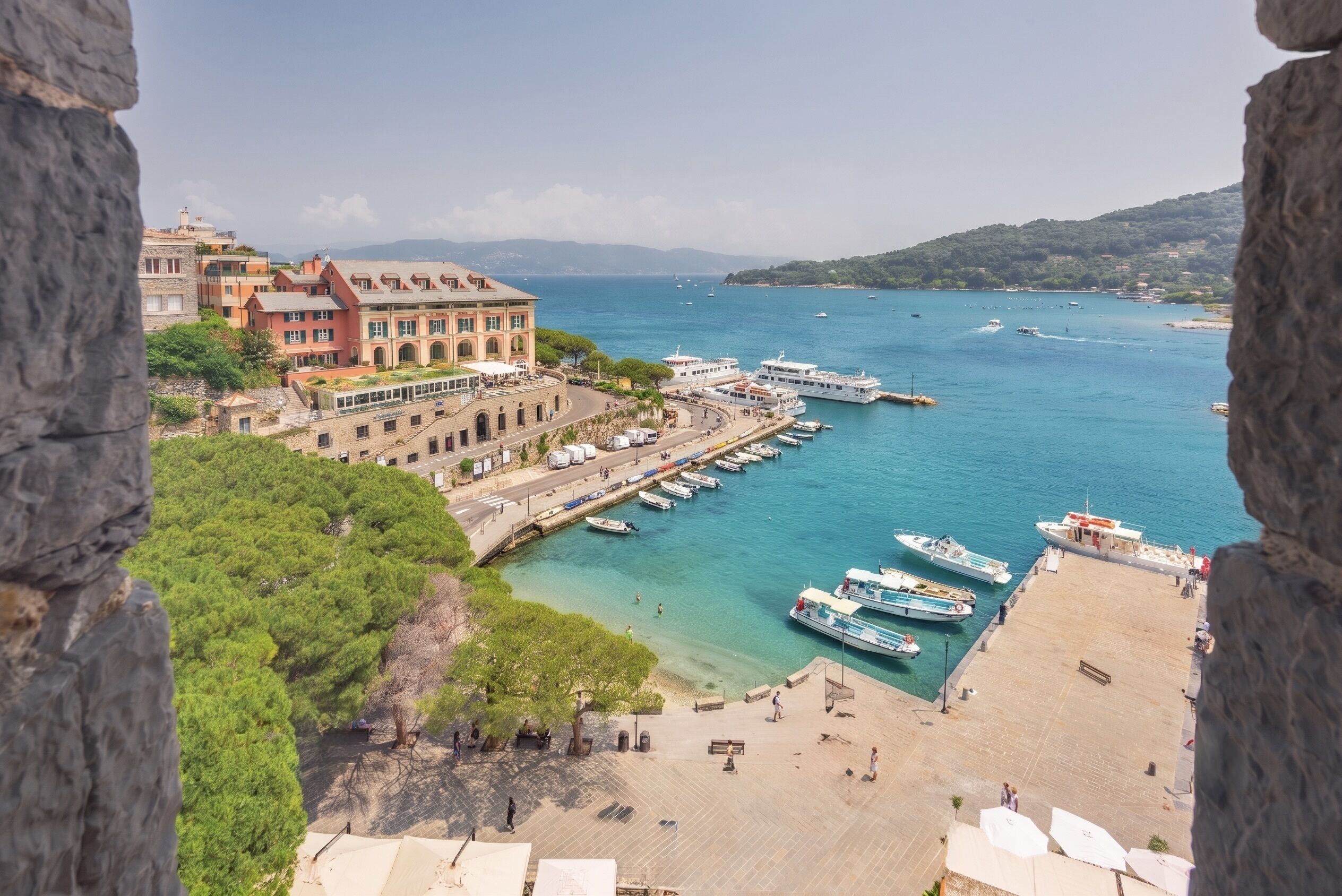 A coastal town with a marina, buildings with balconies, and a clear view of the sea.