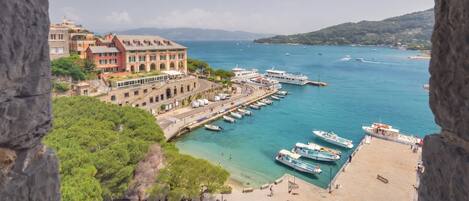 A coastal town with a marina, buildings with balconies, and a clear view of the sea.