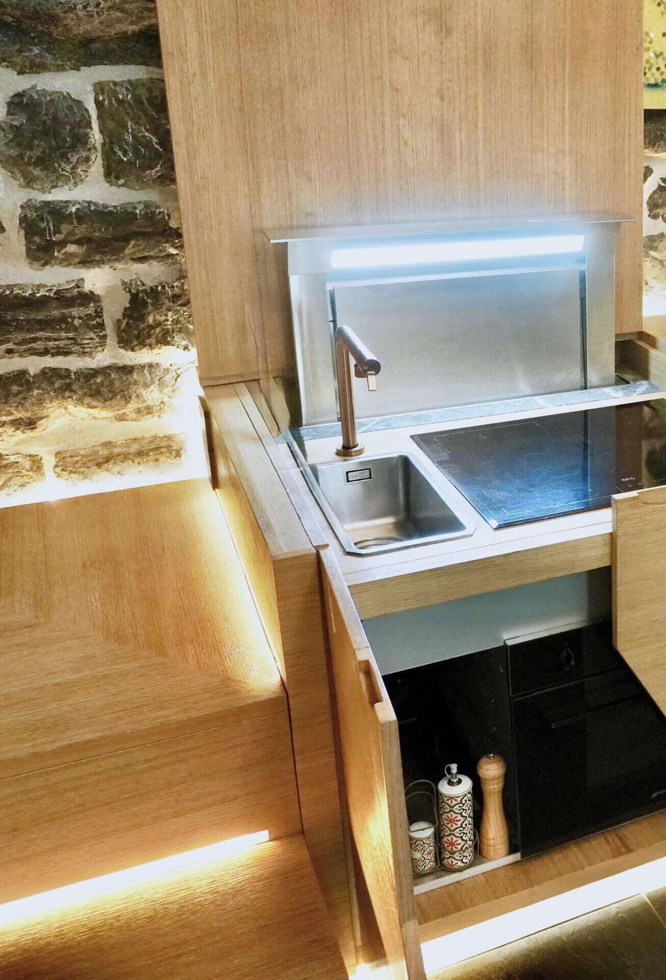 Una cocina moderna con un lavamanos de acero inoxidable, armarios de madera y un horno empotrado.