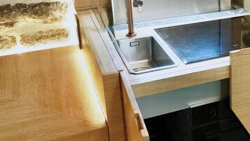 Una cocina moderna con un lavamanos de acero inoxidable, armarios de madera y un horno empotrado.