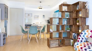 A modern living room with a wooden bookshelf, teal chairs, and a polka dot sofa. - Apartment Pouliguen Centre (Le Pouliguen)